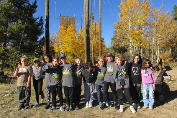A group of students lined up smiling at the camera during ECO Week at CSU's Mountain Campus by the ropes course.