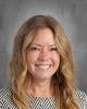 smiling female teacher with  long dark blonde hair in a gray top