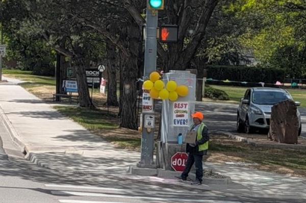 crossing guard with balloons on a street corner - last day of the job