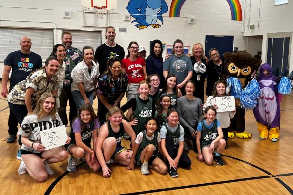 school staff and 4th grade girls basketball game photo - everyone smiling - along with school owl mascot in costume