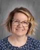 headshot - smiling female teacher with bob cut wearing glasses and a blue top with white polk-a-dots