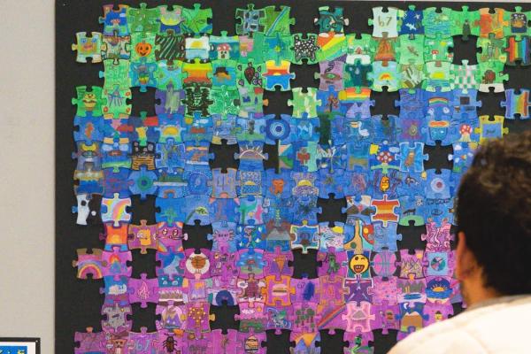 a person looking at the O'Dea art at the district art show - puzzle pieces designed by each student