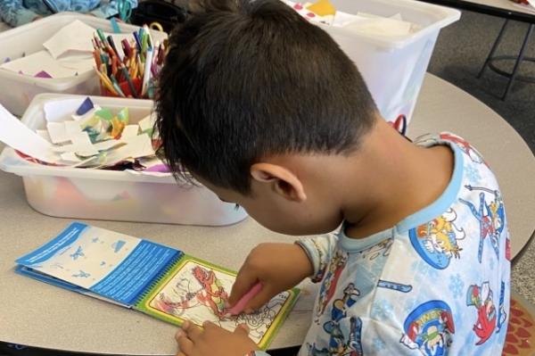 young boy using oil pastels to create a drawing