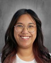 female teacher with long dark hair and glasses in a white top
