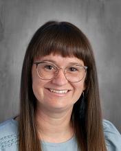 headshot - smiling female teacher with long dark hair, wearing glasses and a light blue top