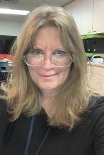 blonde woman smiling looking over glasses on her nose