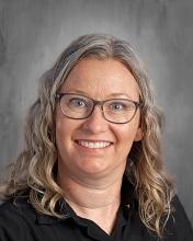 female smiling with gray blonde shoulder length hair glasses and a dark top