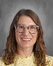 headshot - smiling female teacher long dark hair, wearing glasses, wearing yellow top