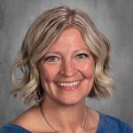 female teacher with short blonde bob cut smiling face blue top