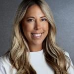 Smiling female, with long blonde hair and a white shirt. 