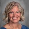 female teacher with short blonde bob cut smiling face blue top