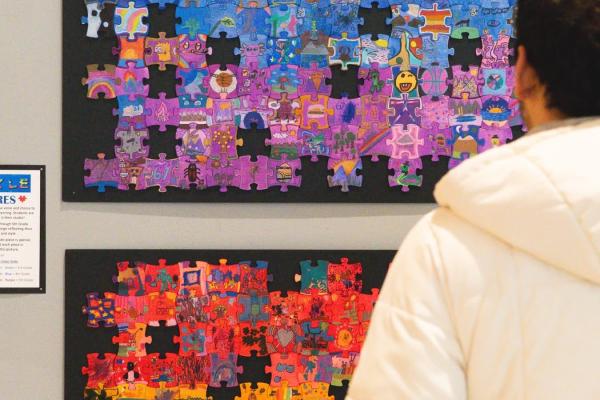 a person looking at the O'Dea art at the district art show - puzzle pieces designed by each student