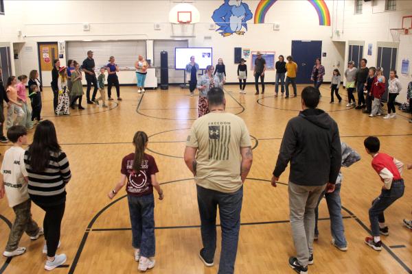 familes with students in a gym learn folk dances from their children 