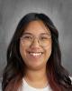 female teacher with long dark hair and glasses in a white top